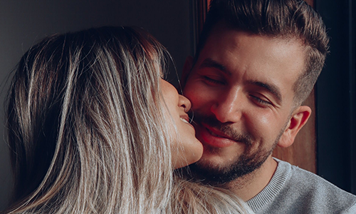 A couple is very close to each other's faces, smiling lovely